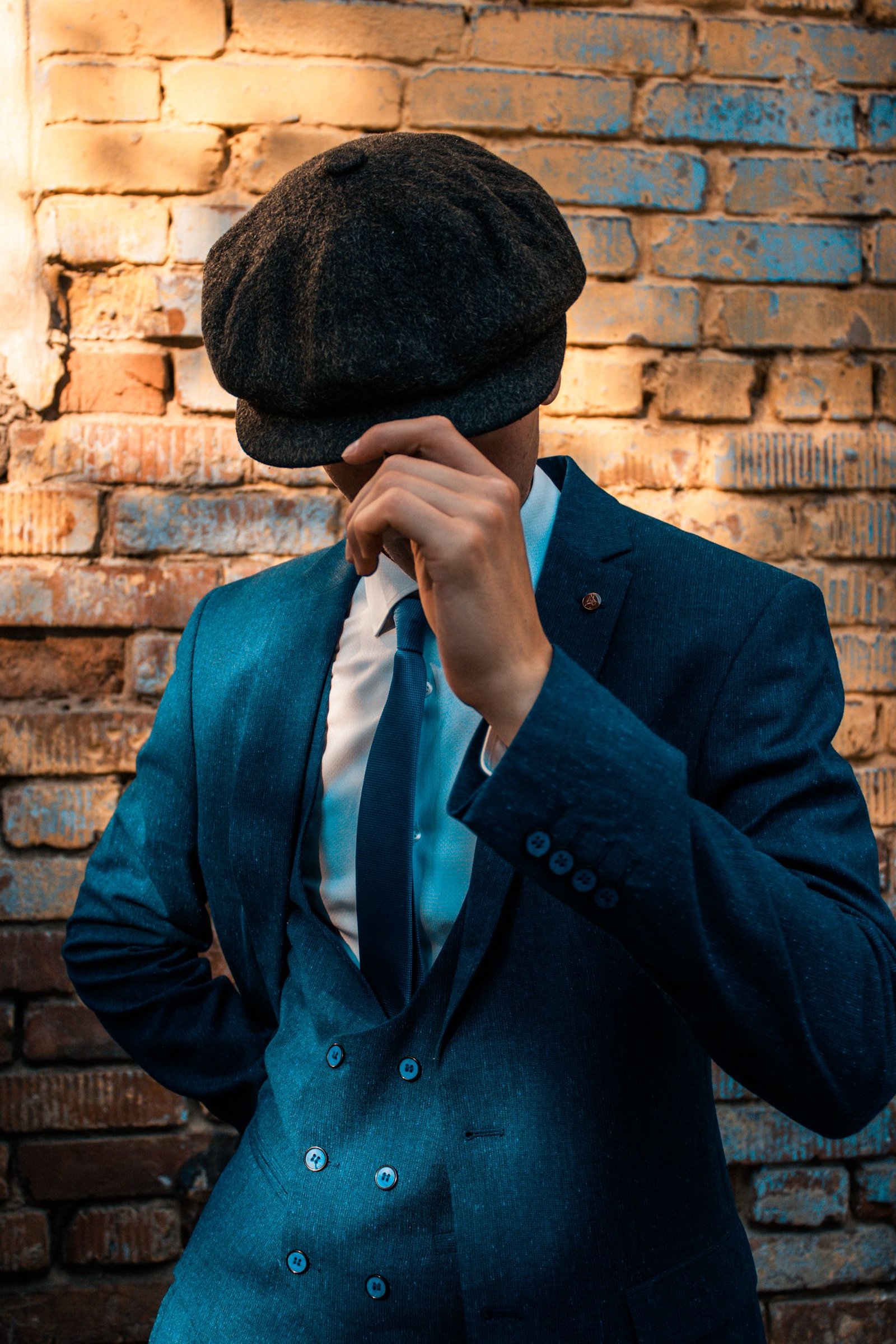 Man wearing a dark wool flat cap with a navy blue suit and tie